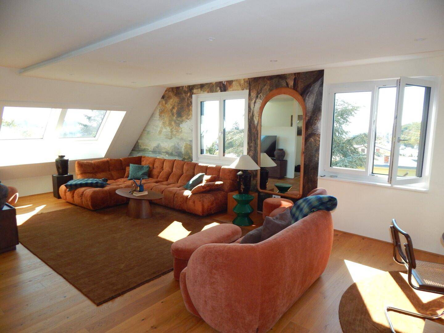 Lichtdurchflutetes Wohnzimmer mit gemütlichen Sofas, Holzboden und schrägen Decken.