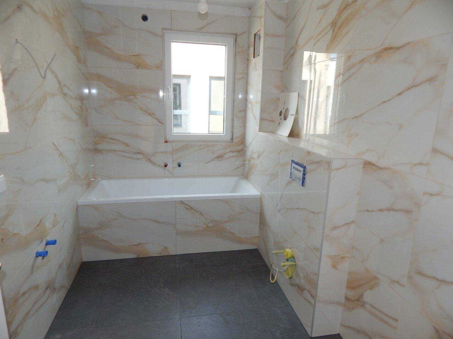 Elegantes Badezimmer mit großformatigen Marmorfliesen und integrierter Badewanne.