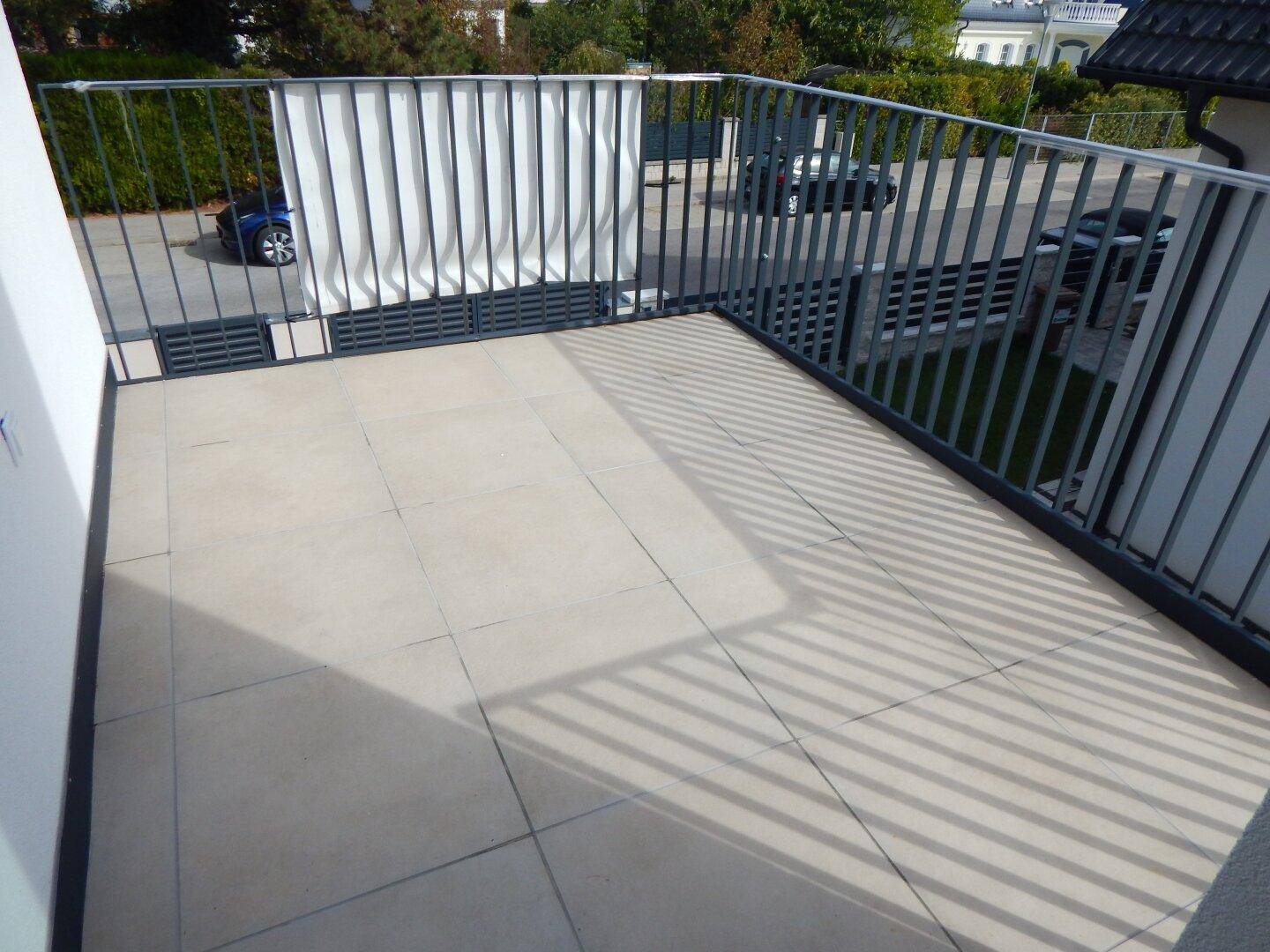 Heller Balkon mit Fliesenboden und Metallgeländer, ideal für entspannte Stunden.