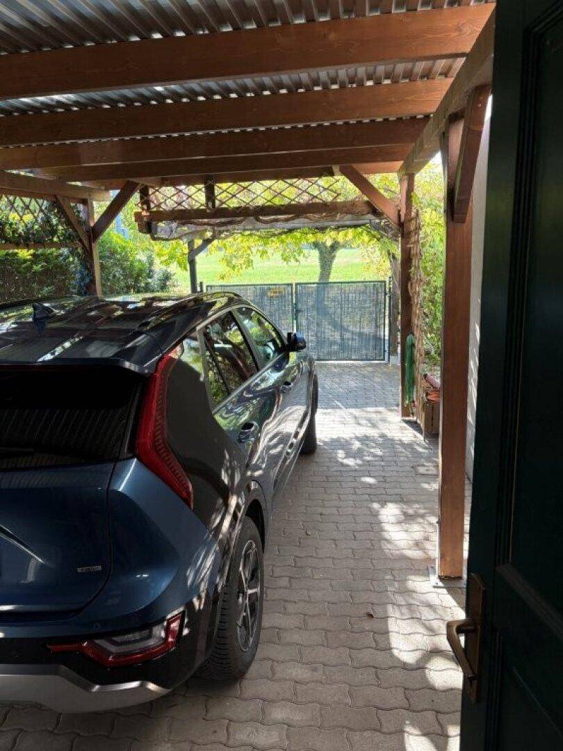 Überdachter Stellplatz für ein Fahrzeug mit gepflastertem Boden und Holzbalkenkonstruktion.