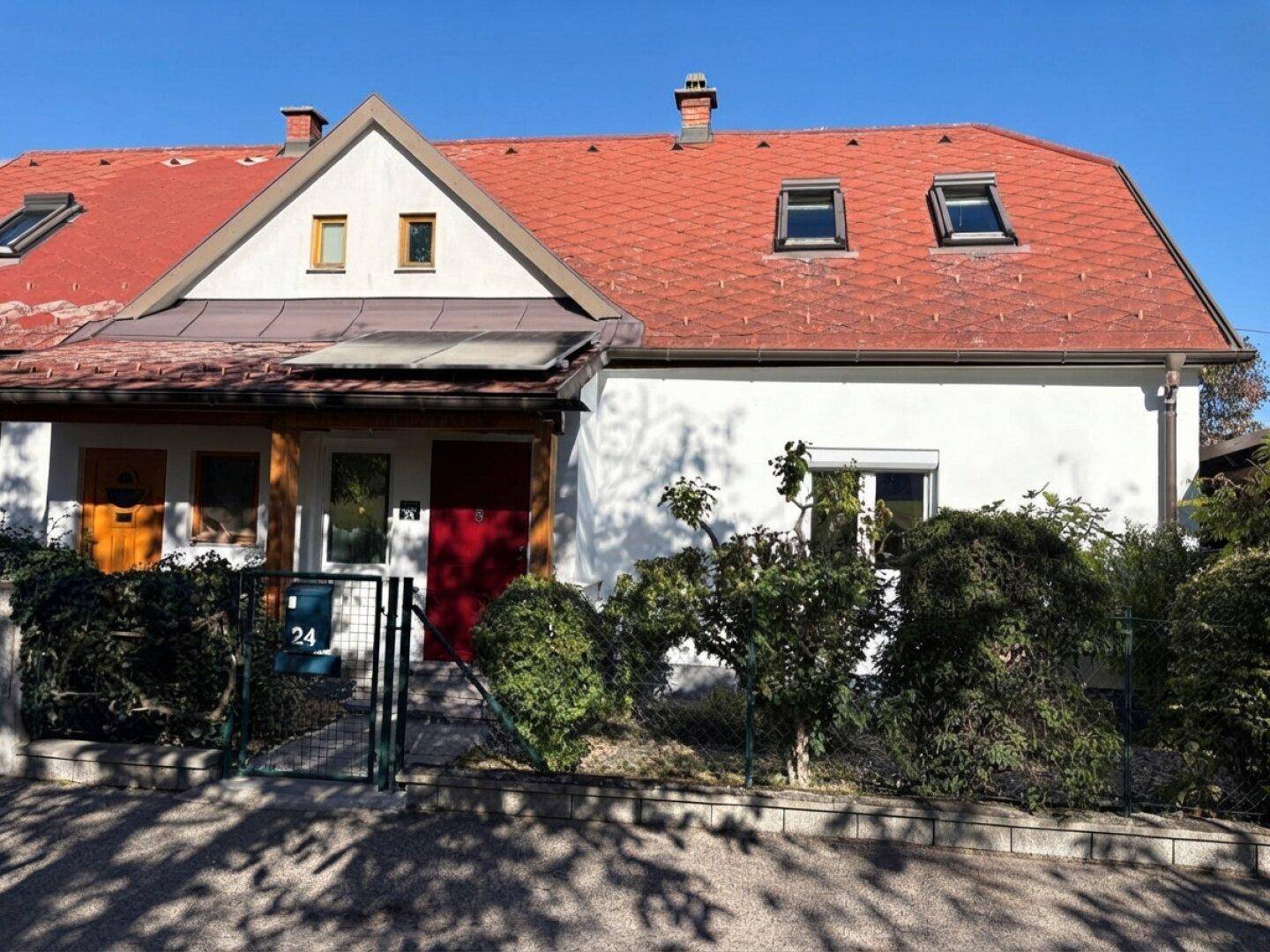 Vorderansicht eines Einfamilienhauses mit rotem Ziegeldach und kleinen Fenstern.