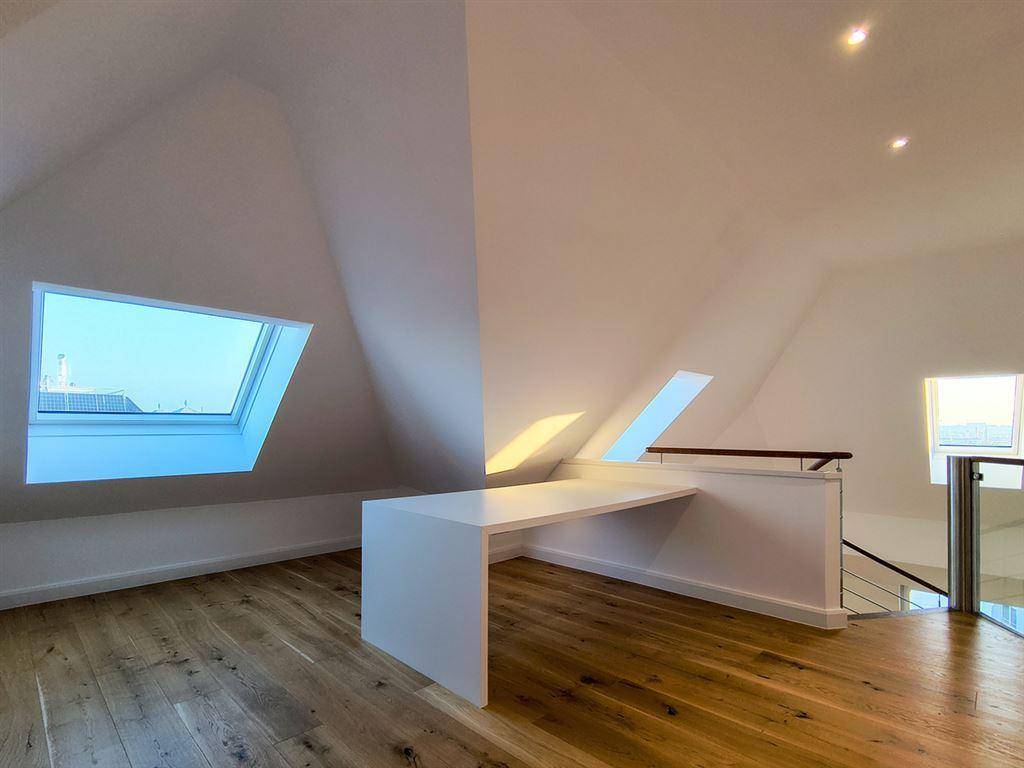 Heller Dachbodenbereich mit Holzboden, schrägen Decken, Oberlichtern und einem integrierten Schreibtisch, ideal als Büro.