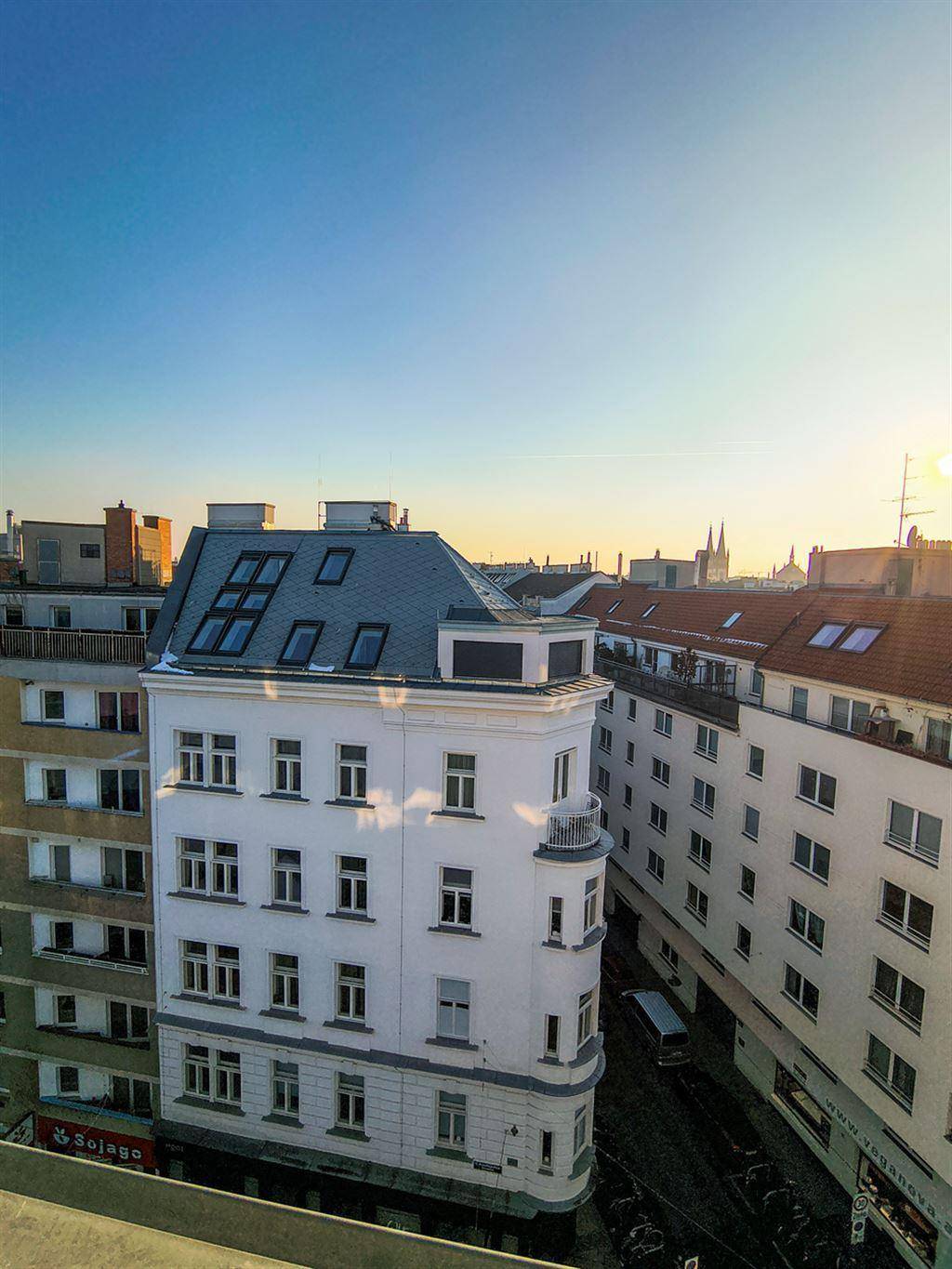 Historisches Gebäude mit markantem Mansarddach und vielen Fenstern, eingebettet in die städtische Architektur.