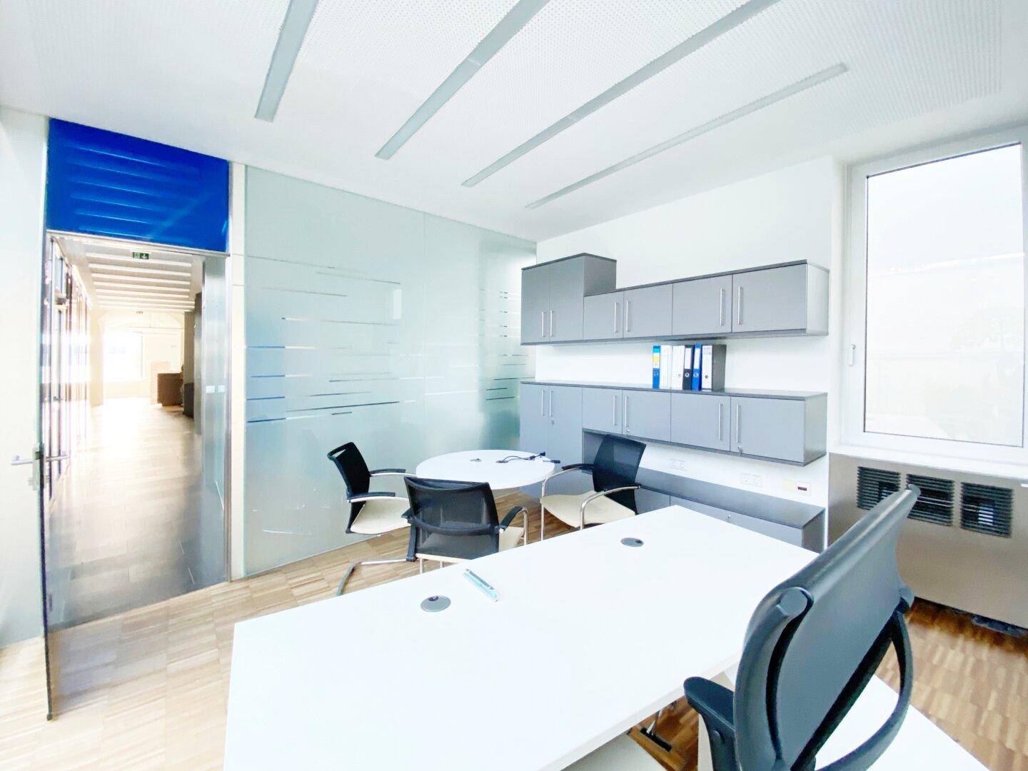 Modernes Büro mit Milchglasabtrennung, die Privatsphäre bietet, und einem Eingangsbereich mit blauen Akzenten.