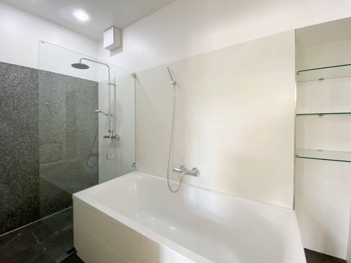 Modernes Badezimmer mit Badewanne, Duschbereich und dunklen Fliesen.