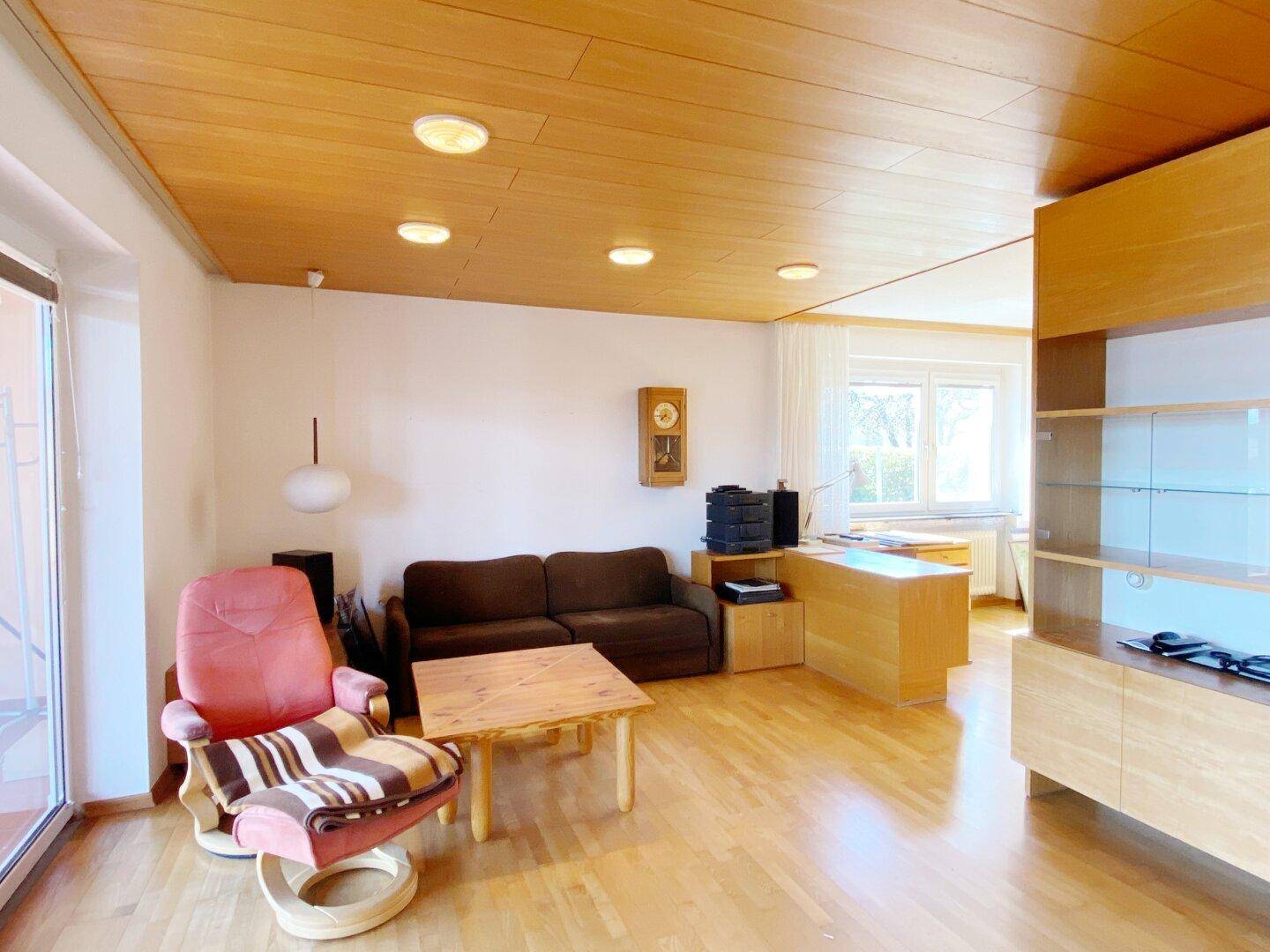 Geräumiges Wohnzimmer mit Holzdecke, Parkettboden und Zugang zum Wintergarten.