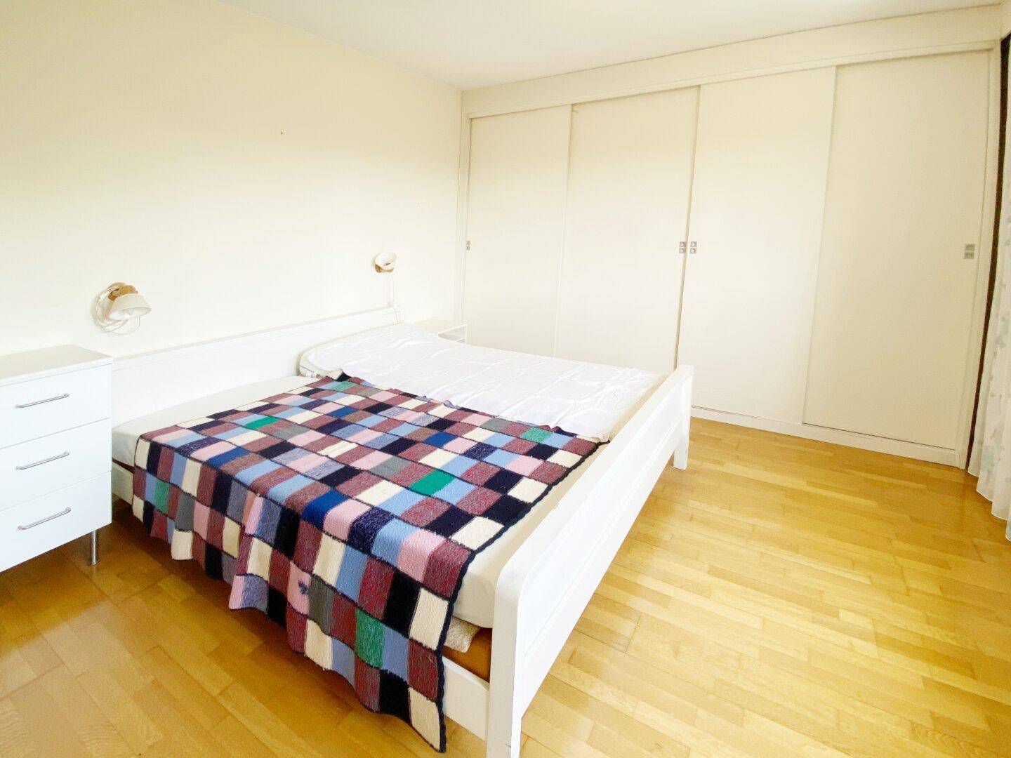 Schlafzimmer mit Doppelbett, Einbauschränken und hellem Parkettboden.