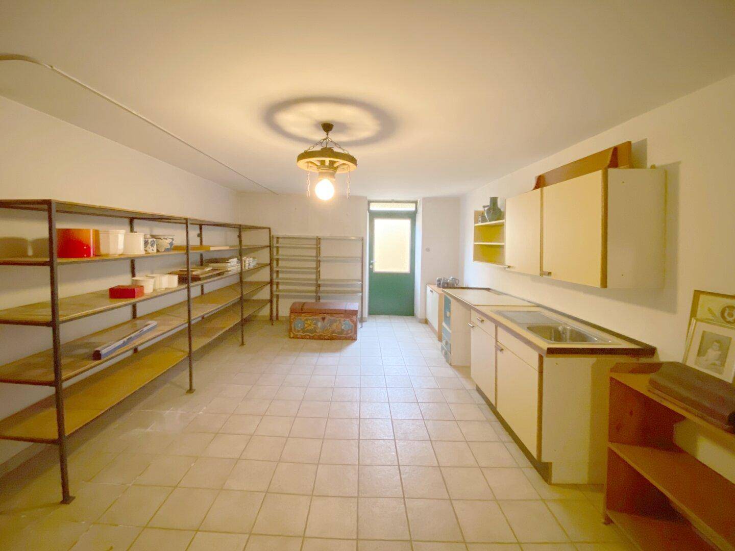 Großer Abstellraum im Keller mit Regalen und Waschbecken, ideal für Vorräte.