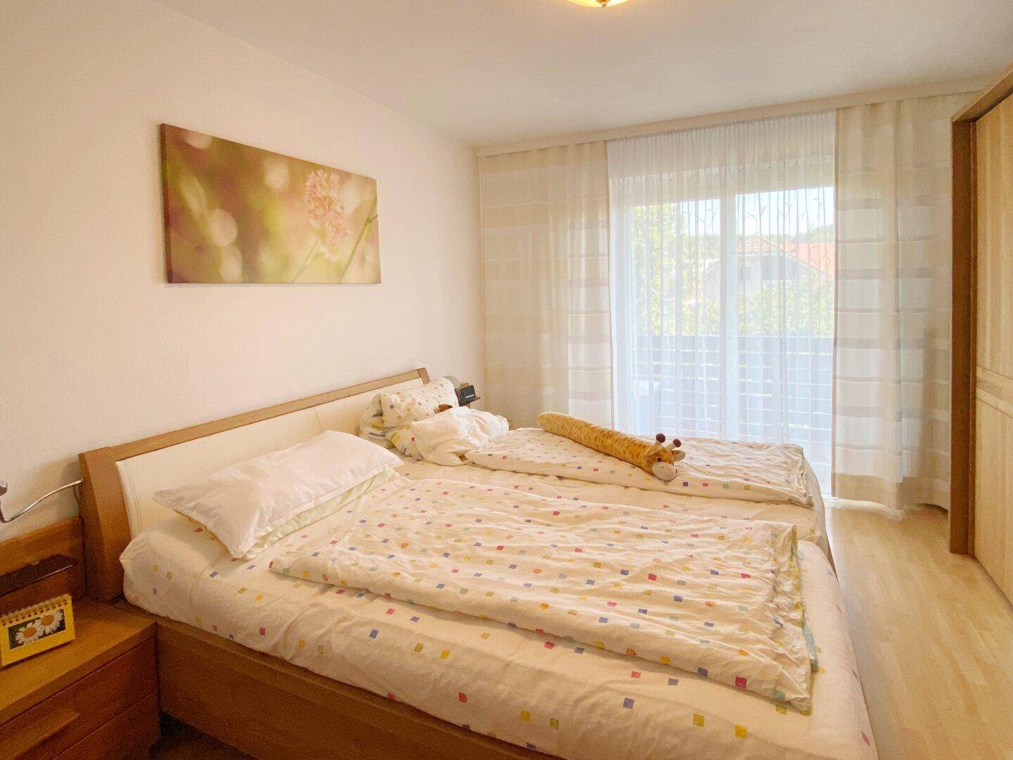 Schlafzimmer mit zwei Einzelbetten, Holzfußboden und großem Fenster mit Vorhängen.