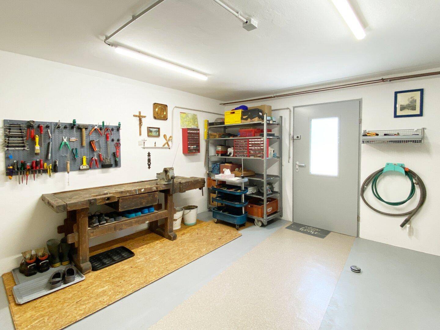 Heller Hobbyraum mit Werkbank, Werkzeugwand und Regalen für Lagerung und Arbeit.