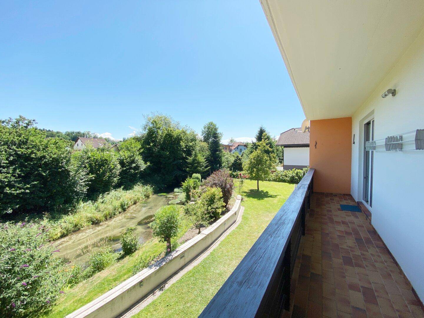 Balkon mit Fliesenboden und weitem Blick auf einen Fluss und die grüne Landschaft.