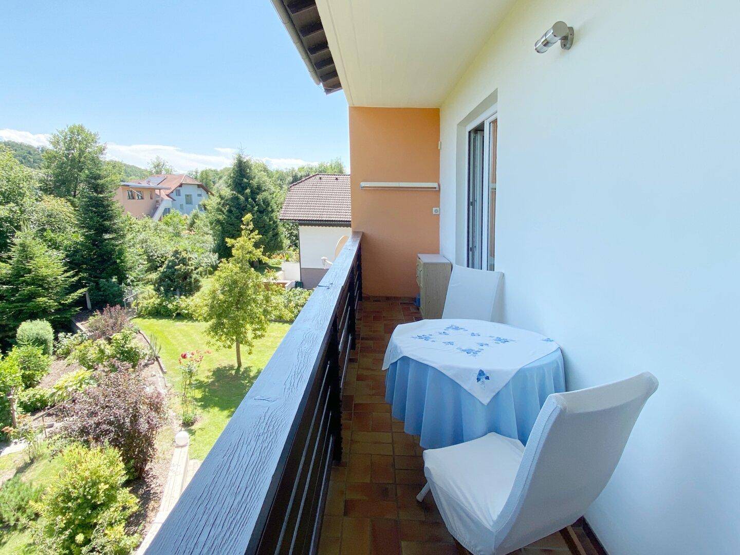 Balkon mit Gartenmöbeln und weitem Blick auf den Garten und die grüne Umgebung.