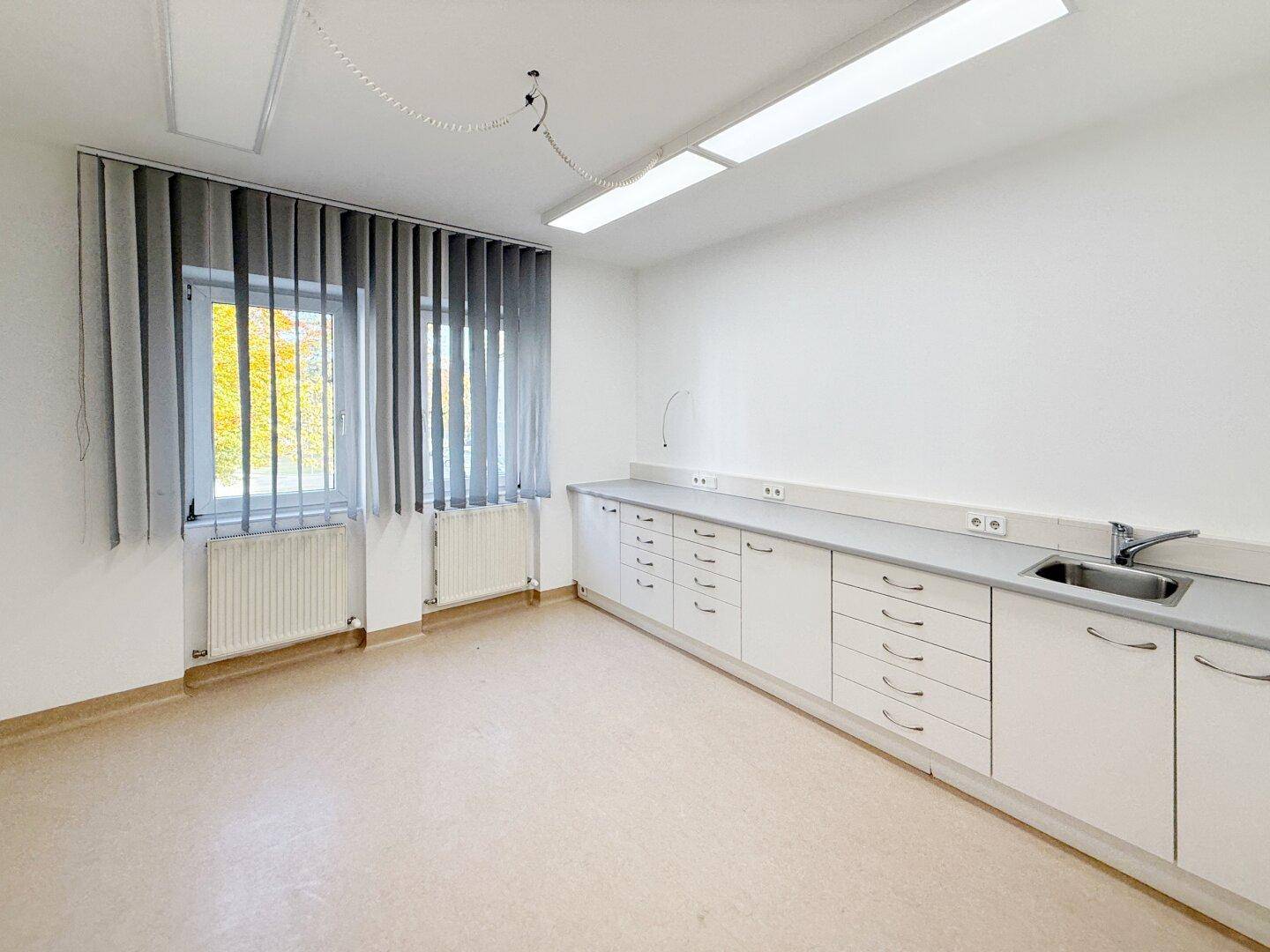 Funktionaler Arbeitsraum mit langer weißer Arbeitsplatte, Spülbecken und vielen Schubladen, ideal für Labor oder Praxis.
