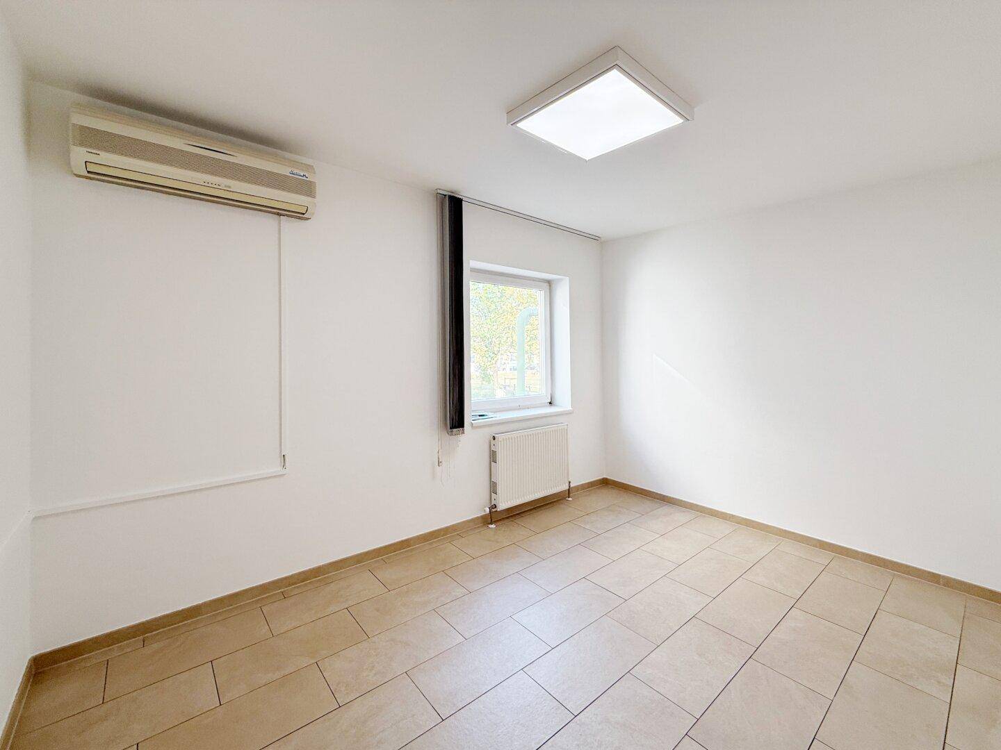 Kleiner, heller Raum mit Fliesenboden, Fenster und Klimaanlage, vielseitig nutzbar als Büro oder Abstellraum.