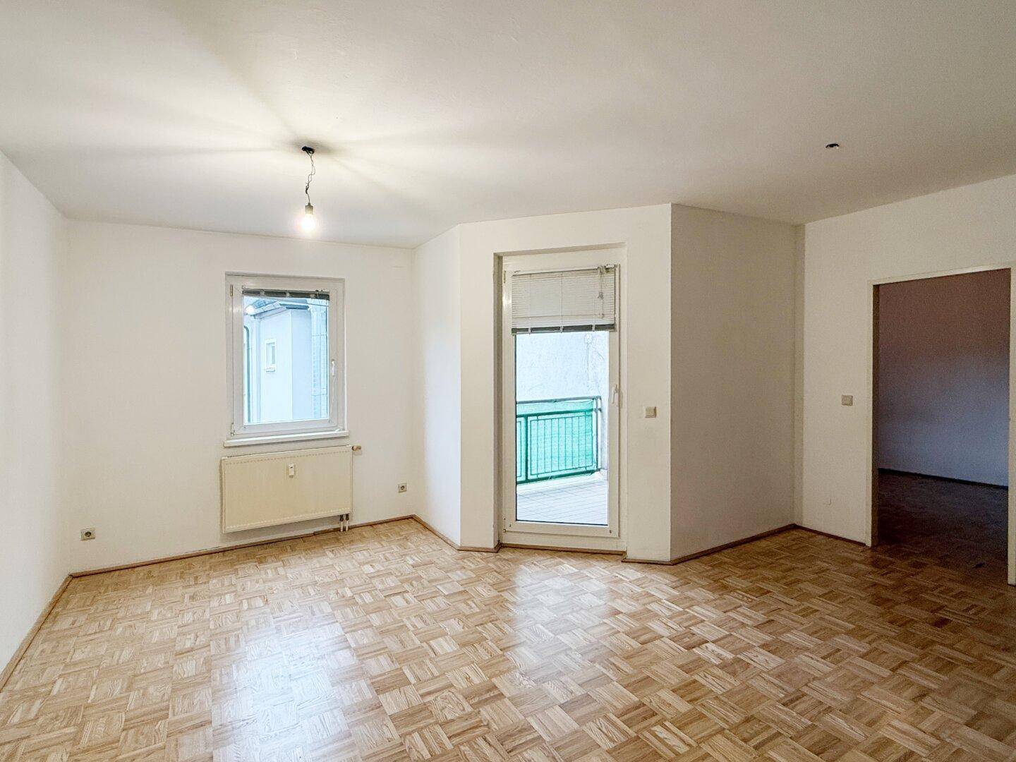 Lichtdurchfluteter Wohnbereich mit Parkettboden und Zugang zu einem Außenbereich.