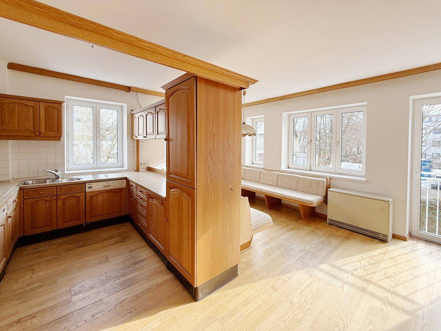 Helle Küche mit Holzschränken, integrierter Sitzbank und Parkettboden.