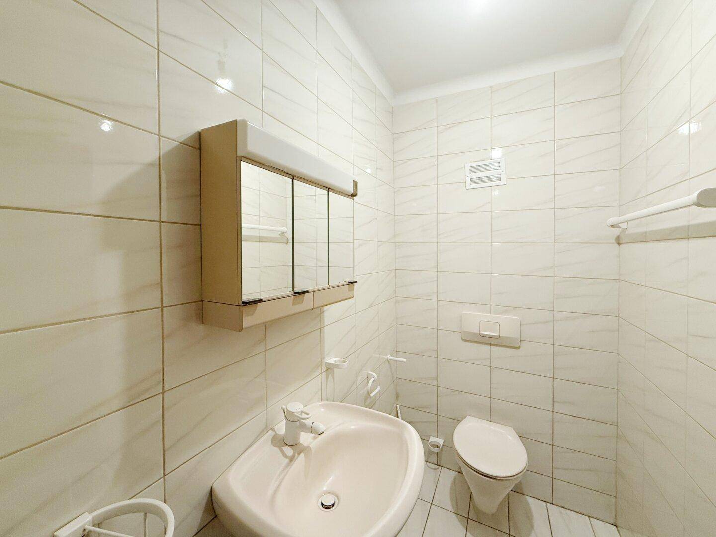 Kleines Gäste-WC mit Waschbecken, Toilette und Spiegelschrank.