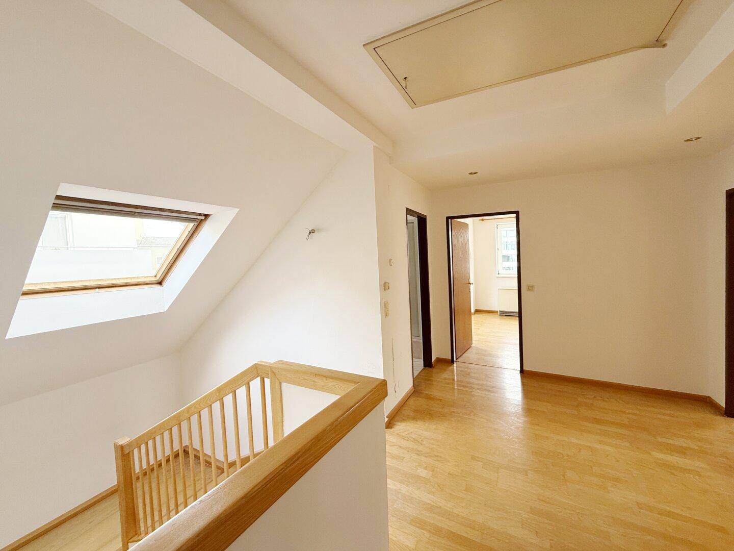 Flur im Obergeschoss mit Dachfenster, Holzgeländer und Parkettboden.