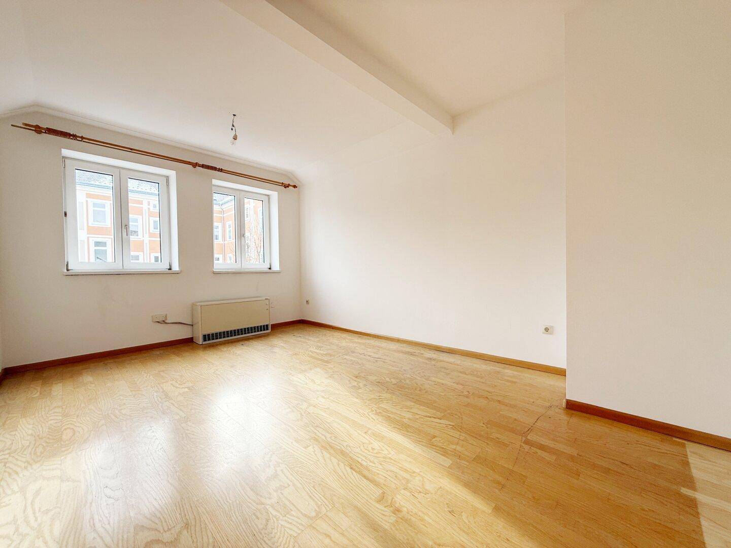 Heller Dachraum mit Parkettboden und Fenstern, ideal als Schlafzimmer.