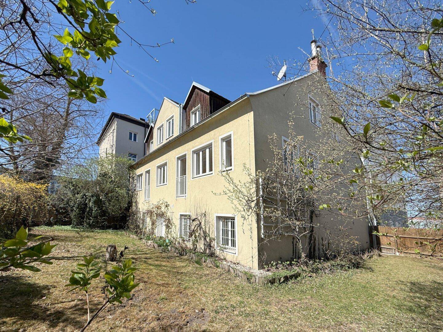 Seitenansicht des Hauses mit großem Gartenbereich und altem Baumbestand.