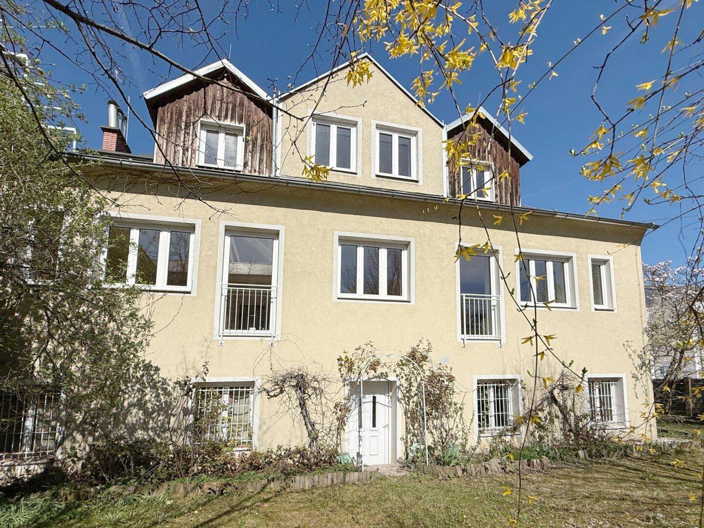 Rückansicht des Hauses mit Garten, Fenstern und französischen Balkonen.
