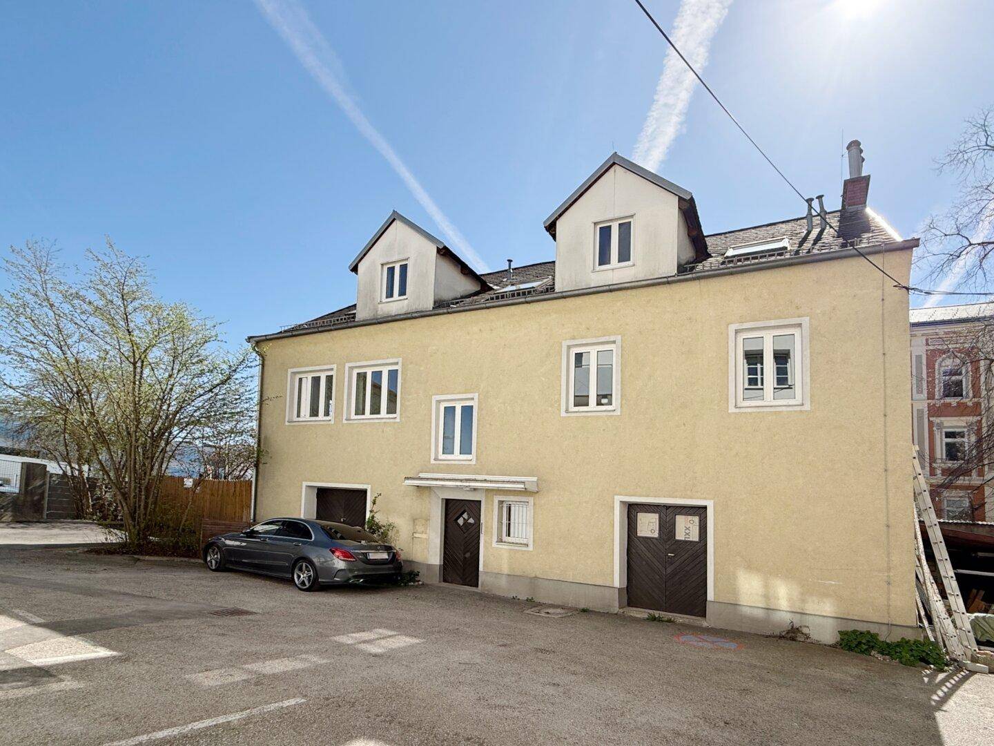 Vorderansicht des Hauses mit mehreren Fenstern und Dachgauben.