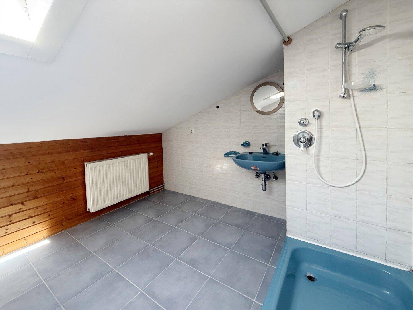 Badezimmer im Dachgeschoss mit Badewanne, Dusche und Holzverkleidung.