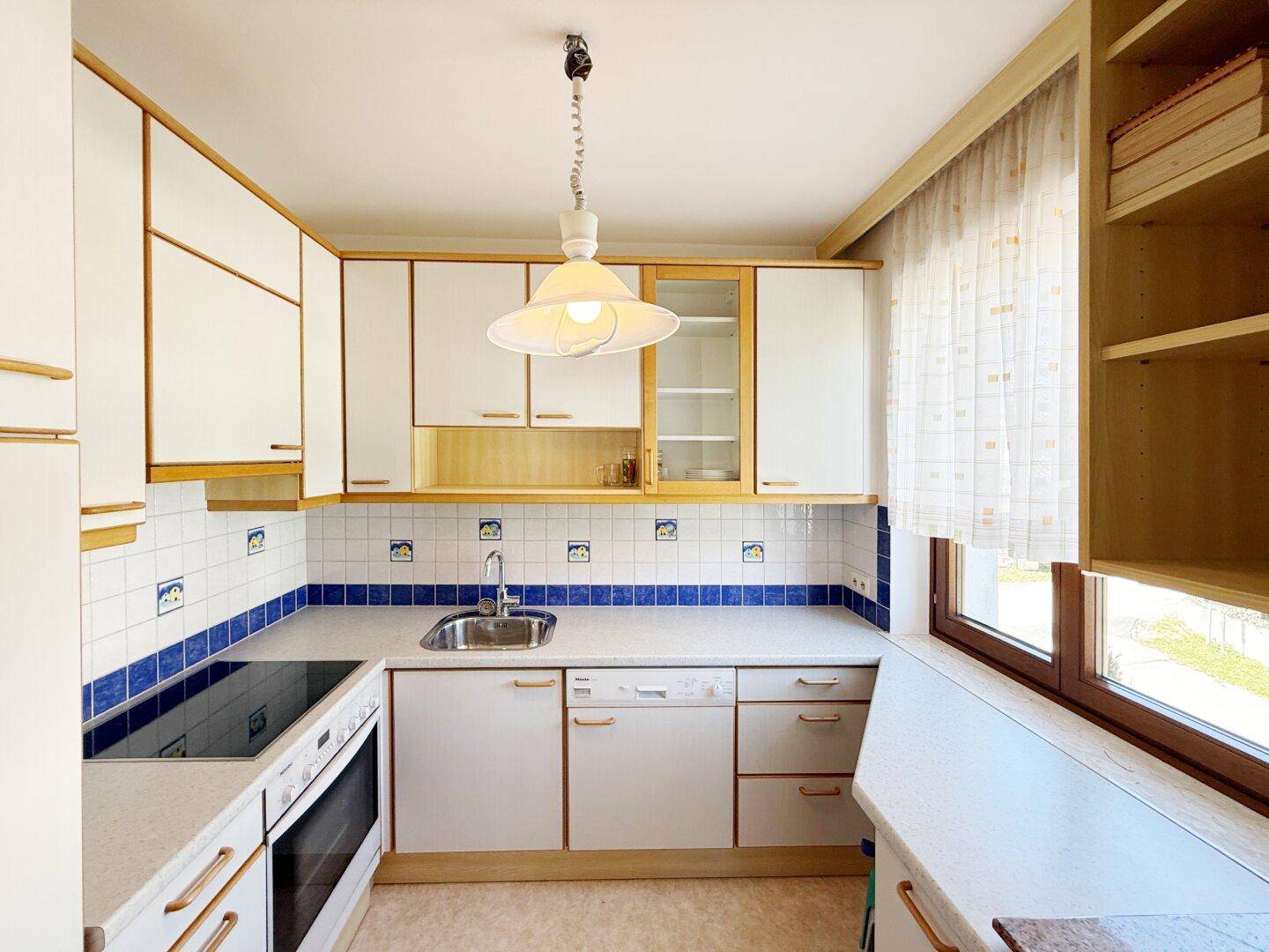 Kleine, funktionale Küche mit weißen Schränken, Fliesen und Fenster.