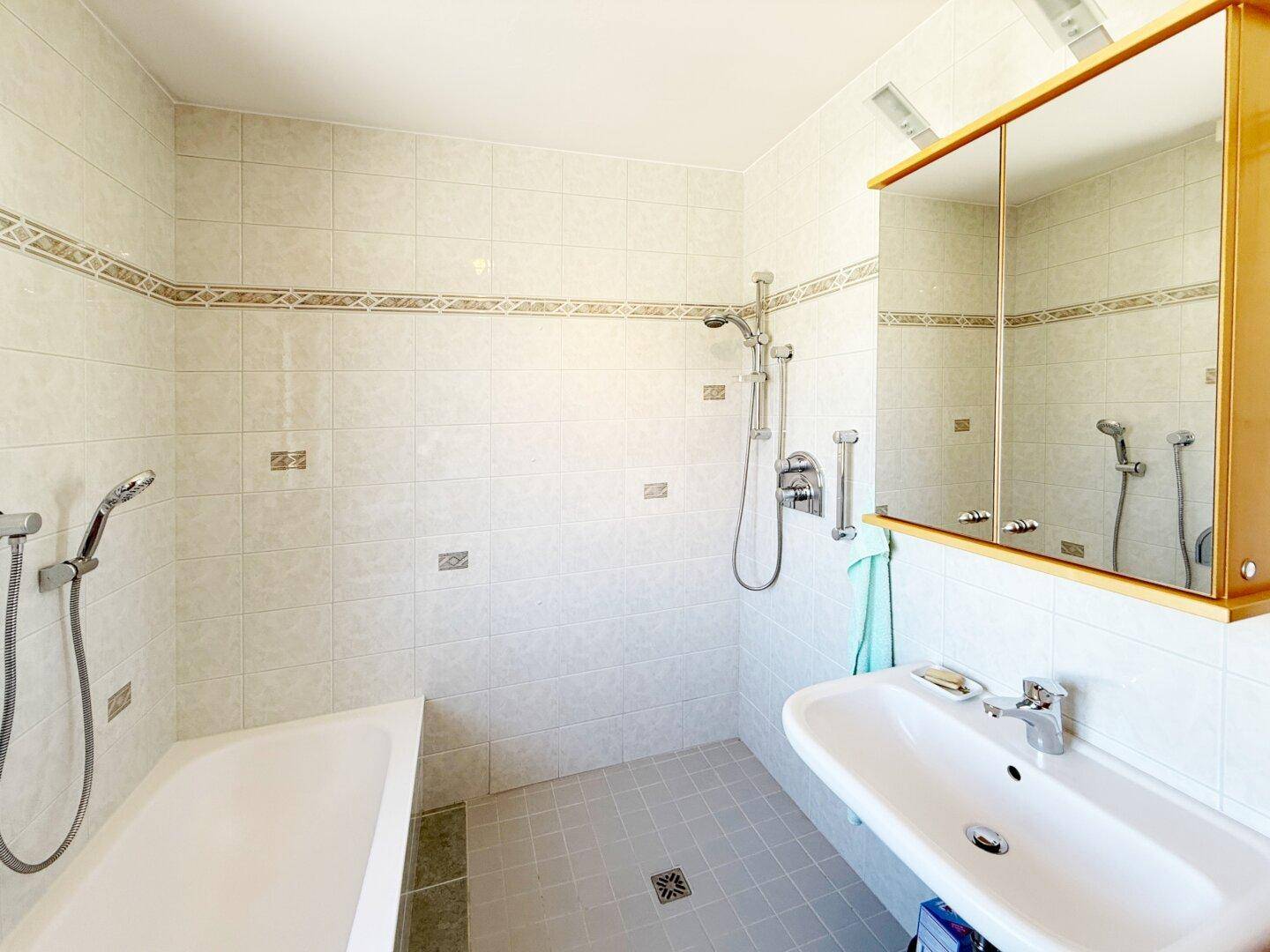 Gefliestes Badezimmer mit Badewanne, Dusche und Waschbecken.