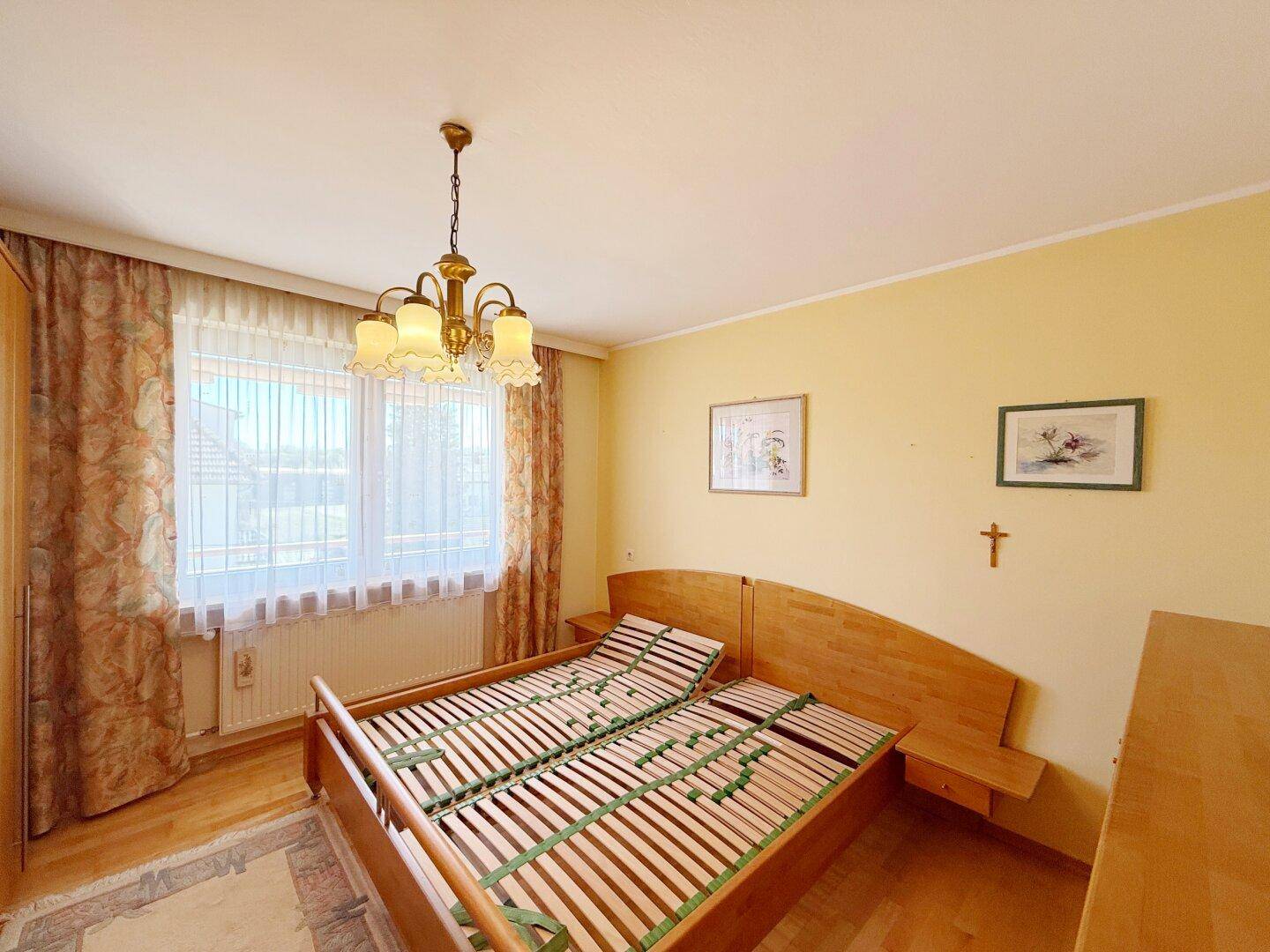 Schlafzimmer mit Holzbetten, Parkettboden und großem Fenster für viel Tageslicht.