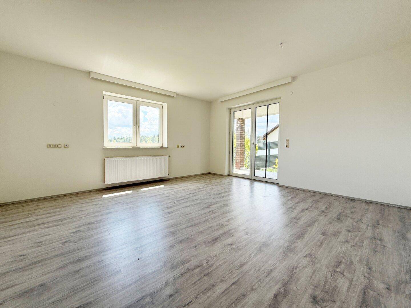 Heller Wohnraum mit modernem Laminatboden und Zugang zur Terrasse oder Balkon.
