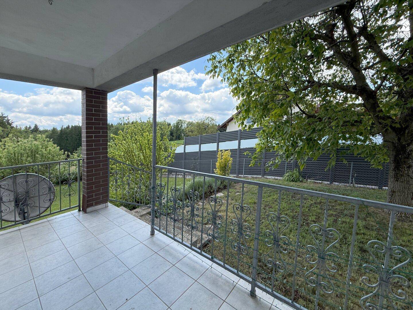 Überdachter Balkon mit Fliesenboden und schmiedeeisernem Geländer mit Weitblick.