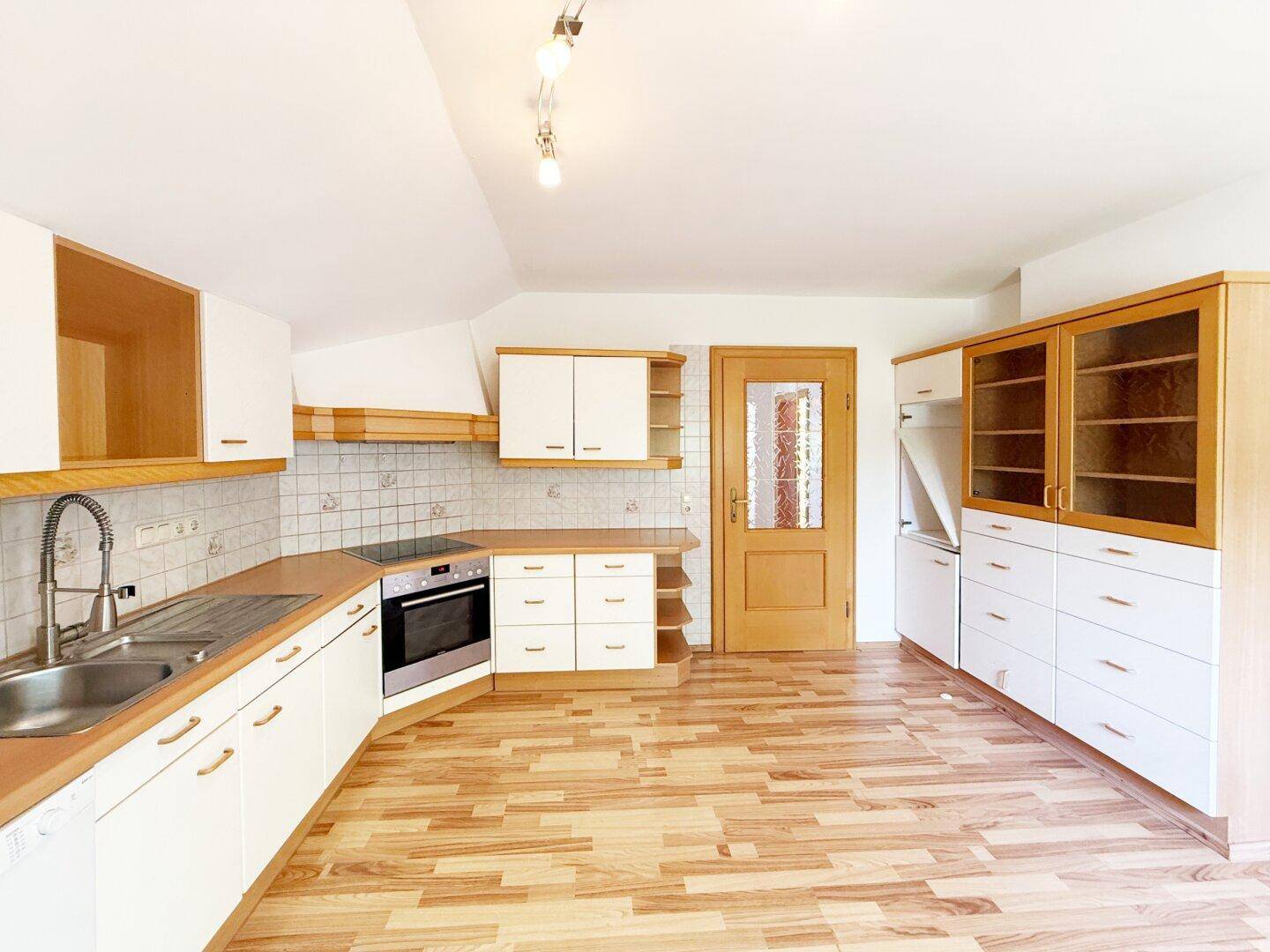 Helle Einbauküche mit weißen Fronten, Holzdetails und integrierten Geräten.