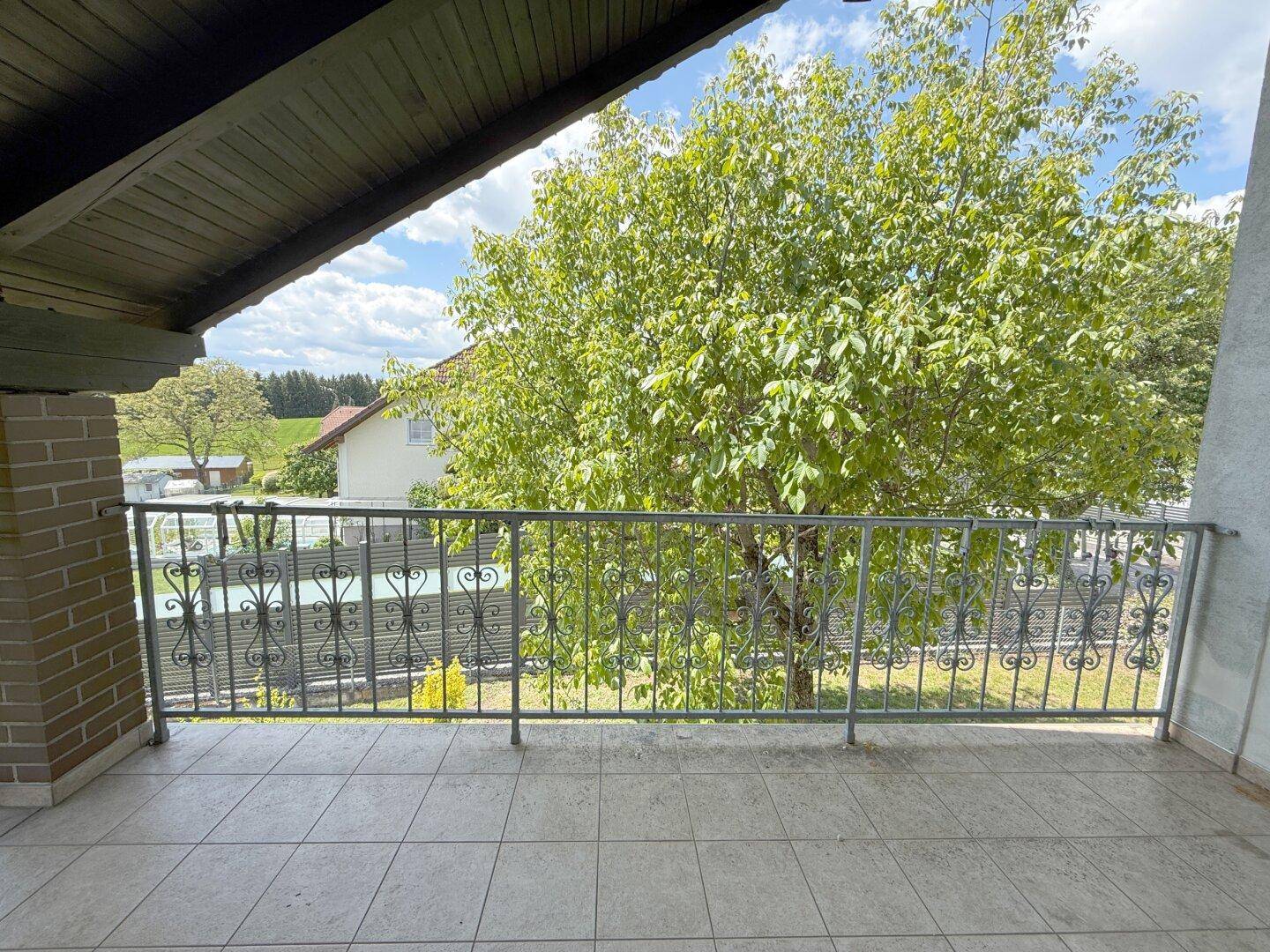 Geräumiger Balkon mit schmiedeeisernem Geländer und Blick auf die Umgebung.