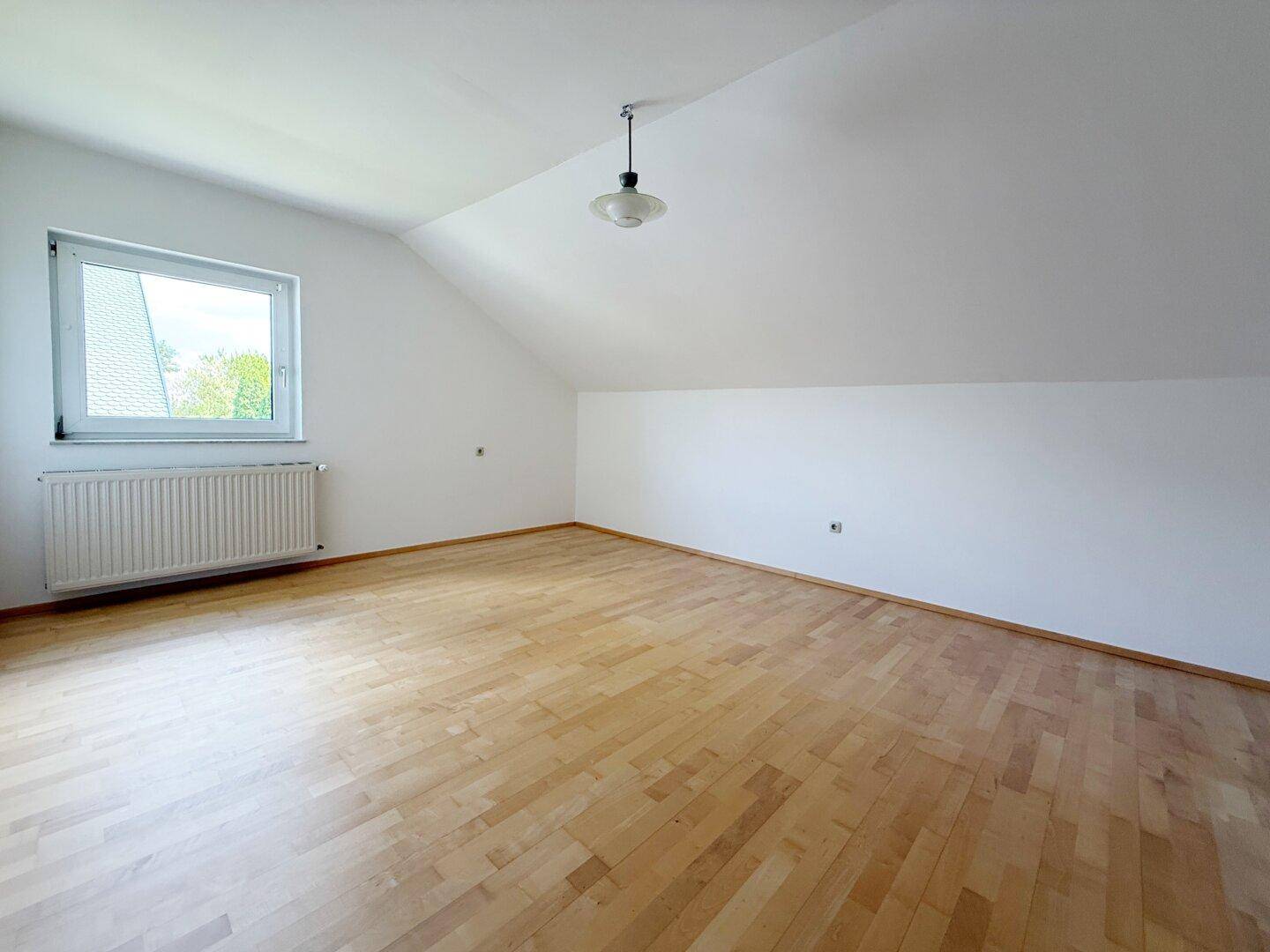 Gemütliches Schlafzimmer im Dachgeschoss mit Holzboden und Dachschräge.