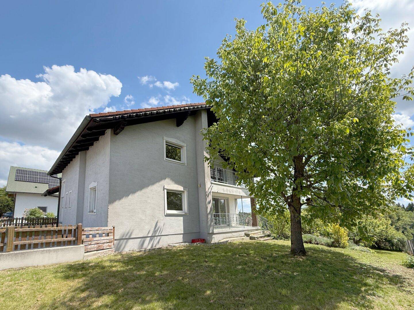 Großer Baum im Gartenbereich neben dem Haus mit Blick auf die grüne Umgebung.