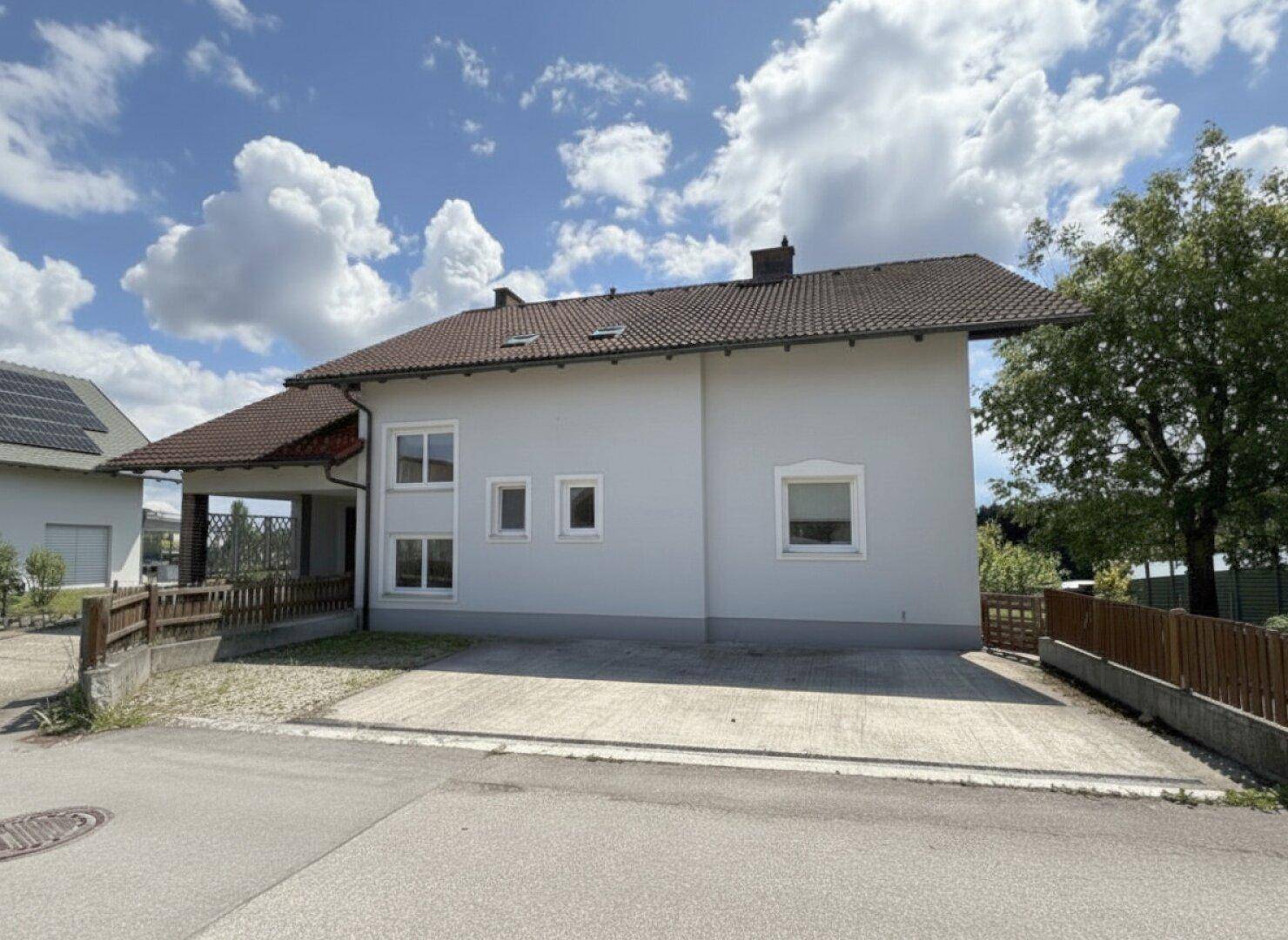 Seitenansicht des Hauses mit gepflasterter Zufahrt und angrenzendem Gartenbereich.