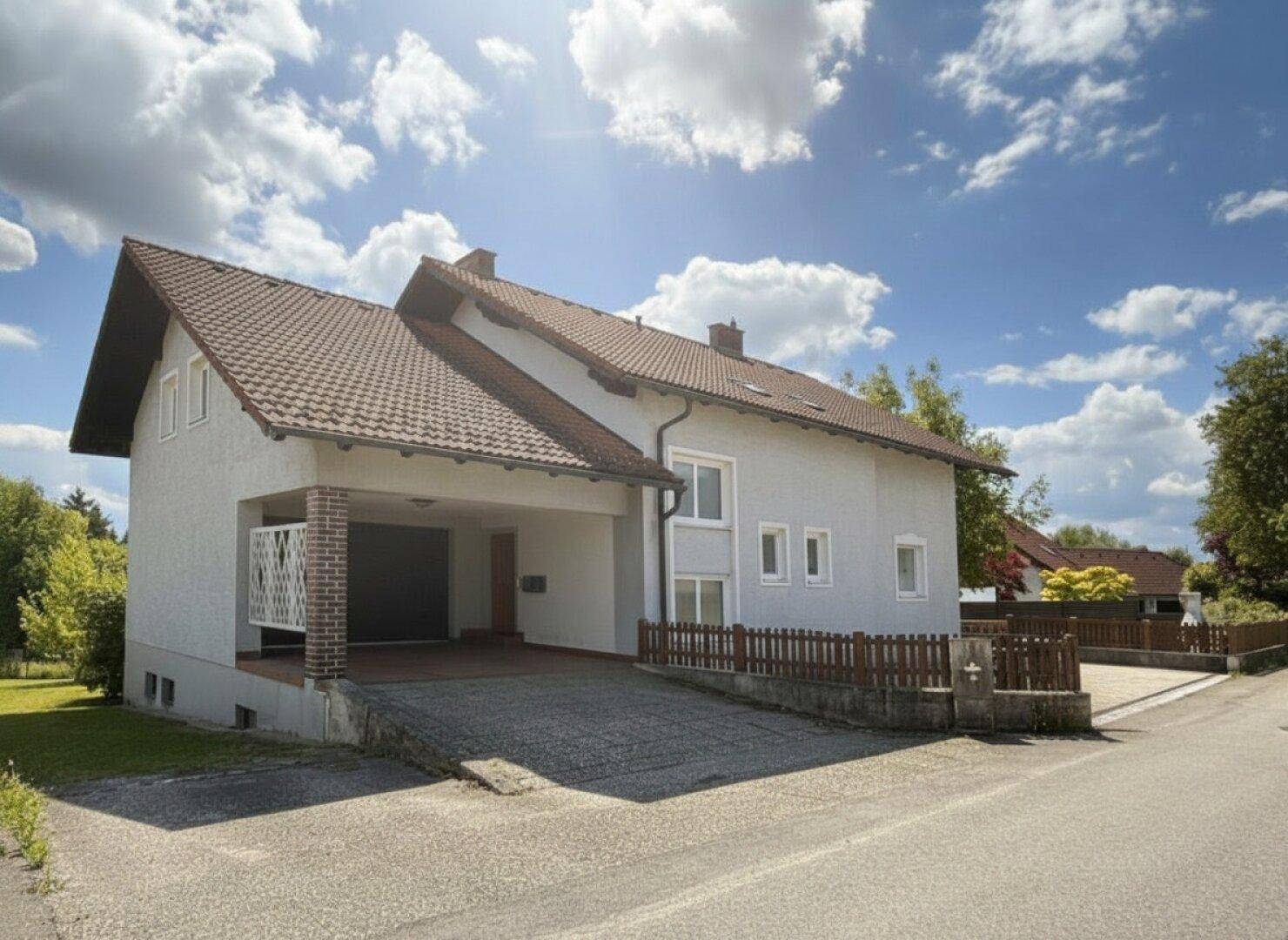 Vorderansicht des Einfamilienhauses mit Carport und Zufahrt unter blauem Himmel.