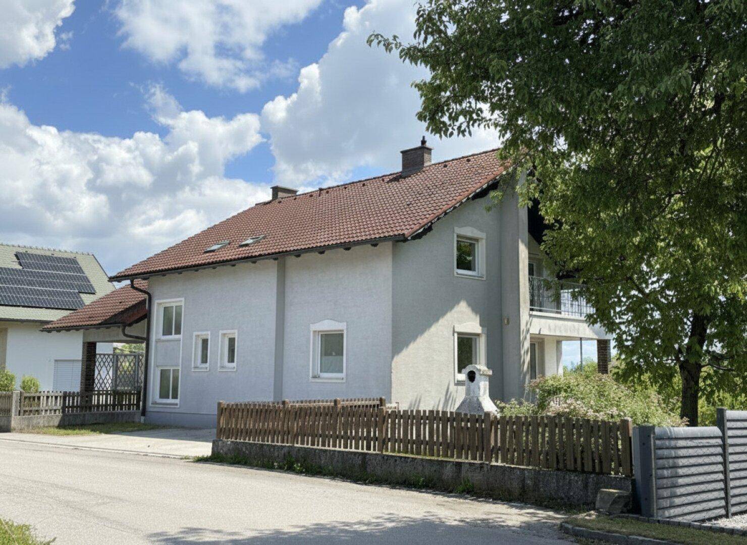 Seitenansicht des Hauses mit Zaun und Blick auf die Umgebung an einem sonnigen Tag.