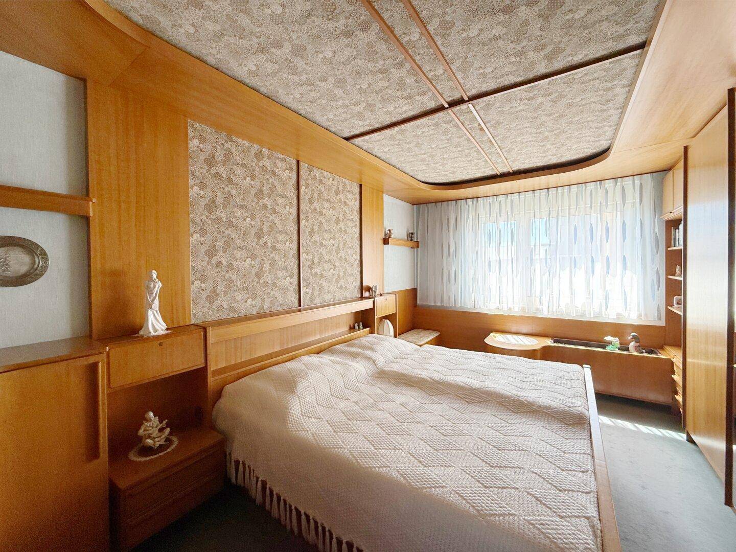 Schlafzimmer mit umfassender Holzvertäfelung, Einbaumöbeln und Doppelbett.