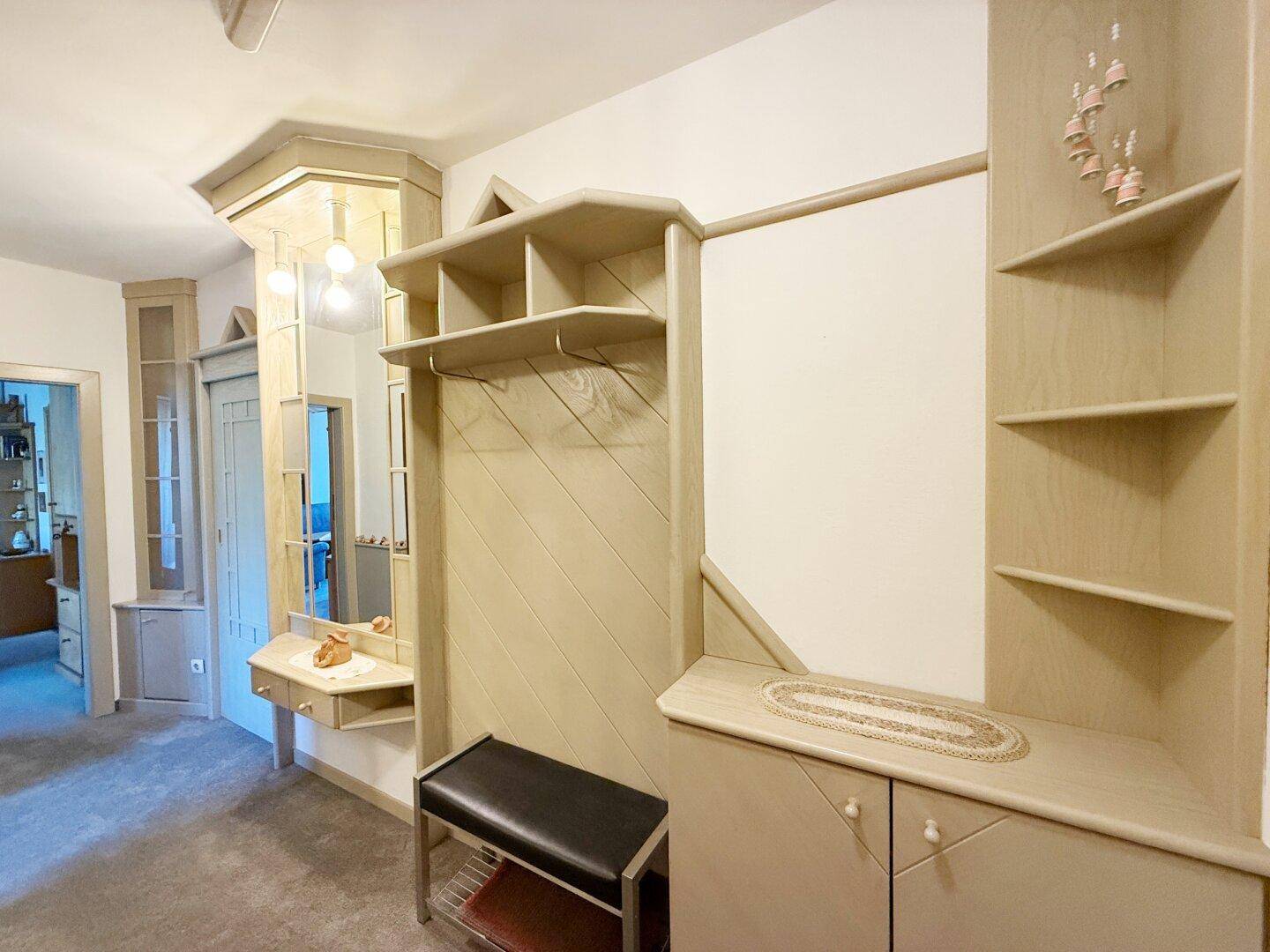 Eingangsbereich mit Einbauschränken, Spiegel und Garderobe in hellem Holzton.