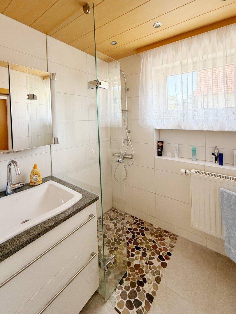 Modernes Badezimmer mit begehbarer Dusche, Steinboden und Holzdecke.