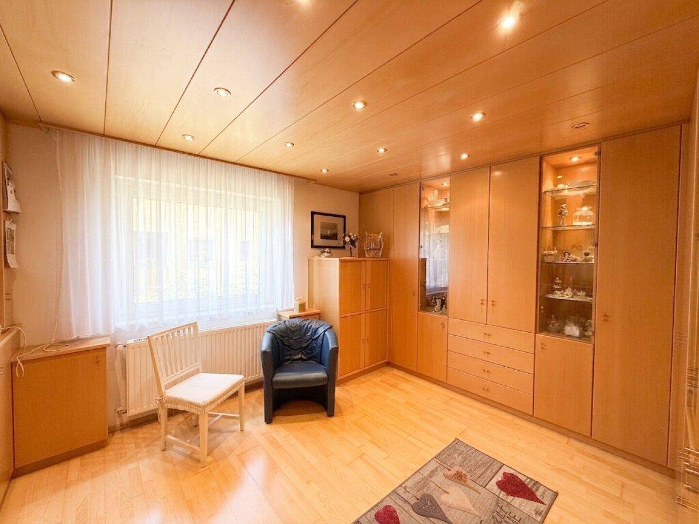 Helles Zimmer mit Einbauschränken, Holzdecke und großem Fenster.
