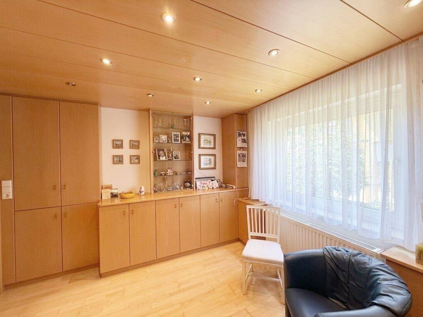 Geräumiges Zimmer mit Holzschränken, Vitrinen und hellem Parkettboden.