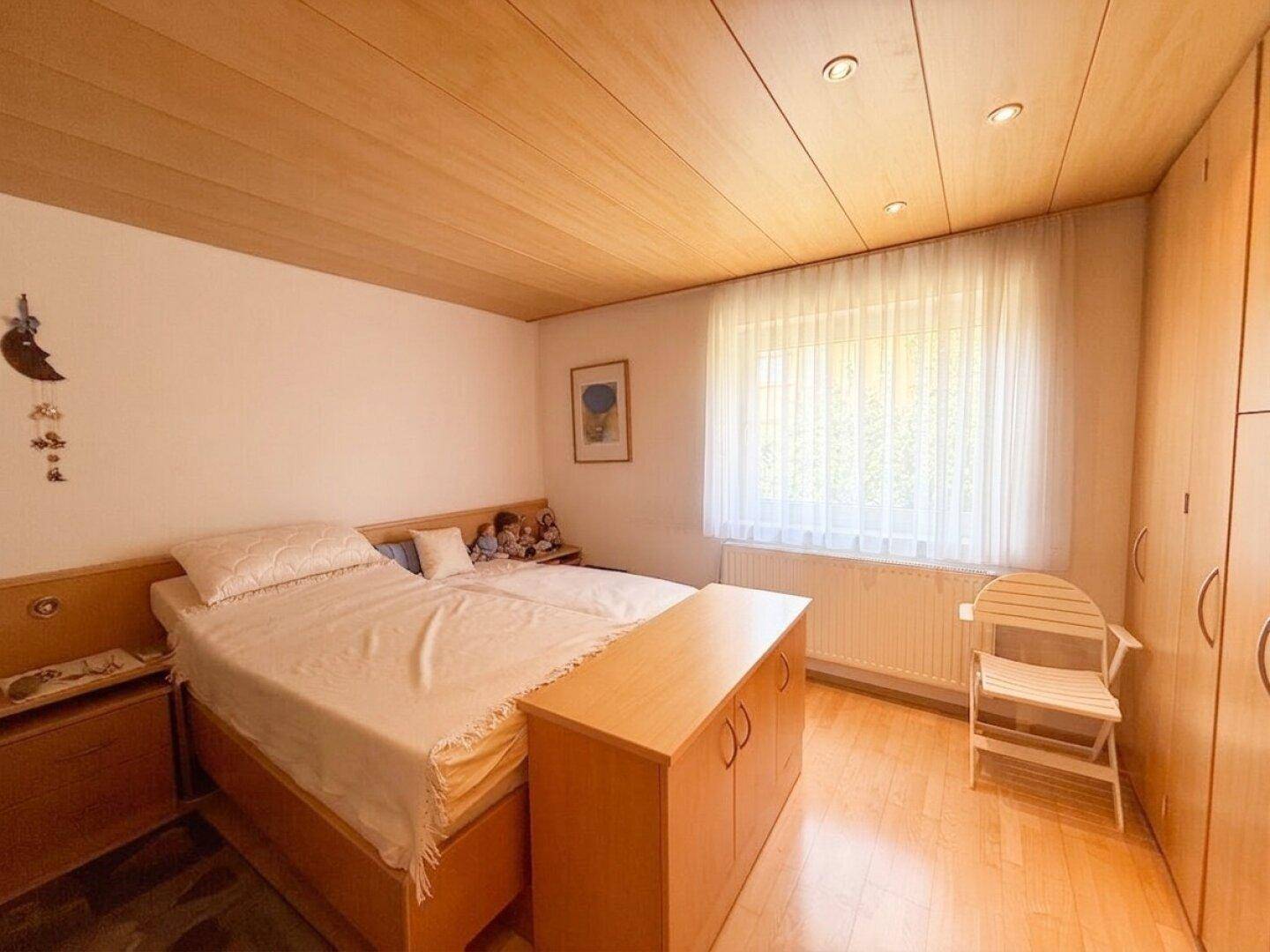Helles Schlafzimmer mit Doppelbett, Holzdecke und Einbauschränken.