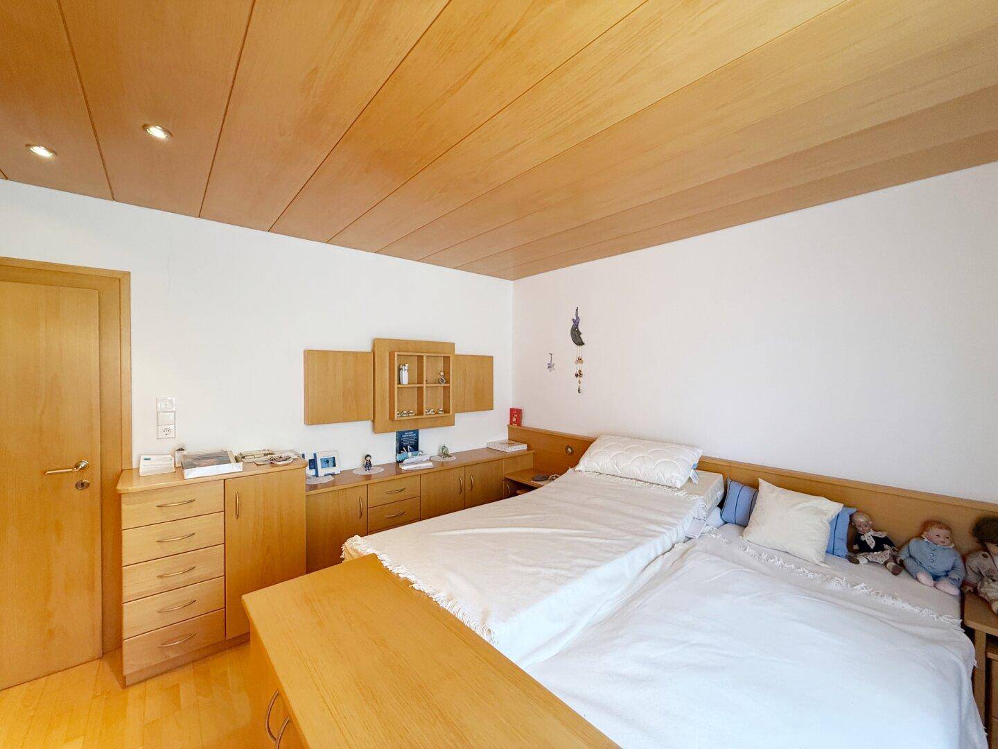 Gemütliches Schlafzimmer mit zwei Einzelbetten, Holzmöbeln und Holzdecke.