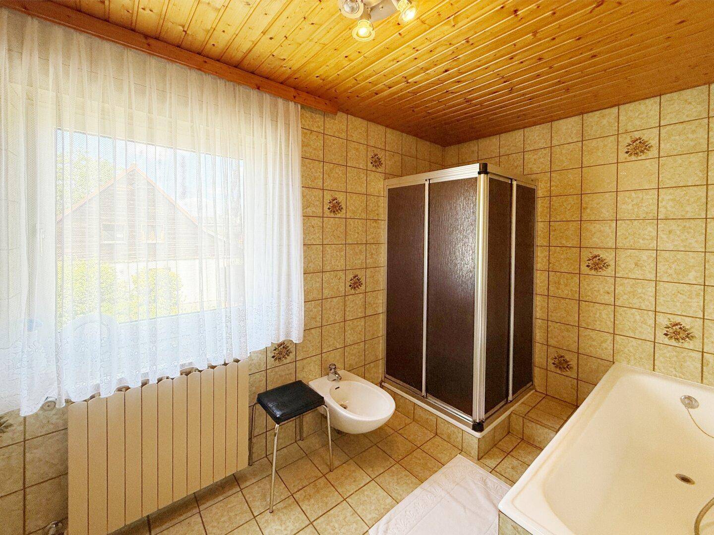 Badezimmer mit Duschkabine, Badewanne, Bidet und Holzdecke.