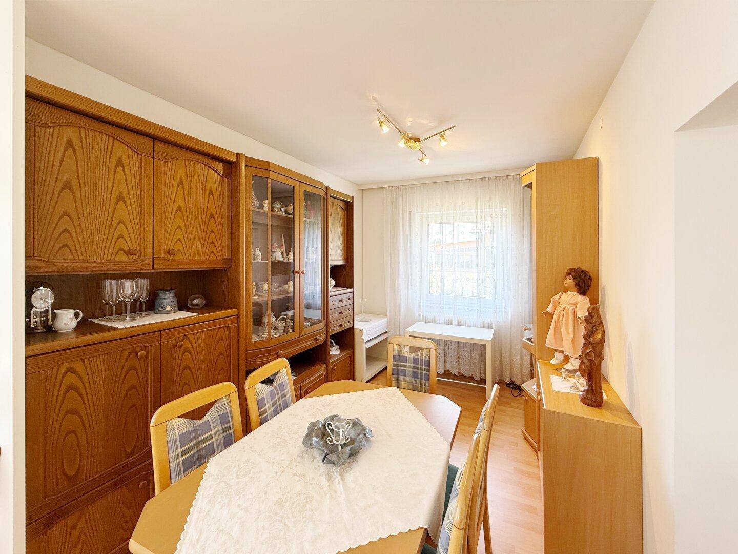 Traditioneller Essbereich mit Holzmöbeln, Vitrinenschrank und großem Fenster.