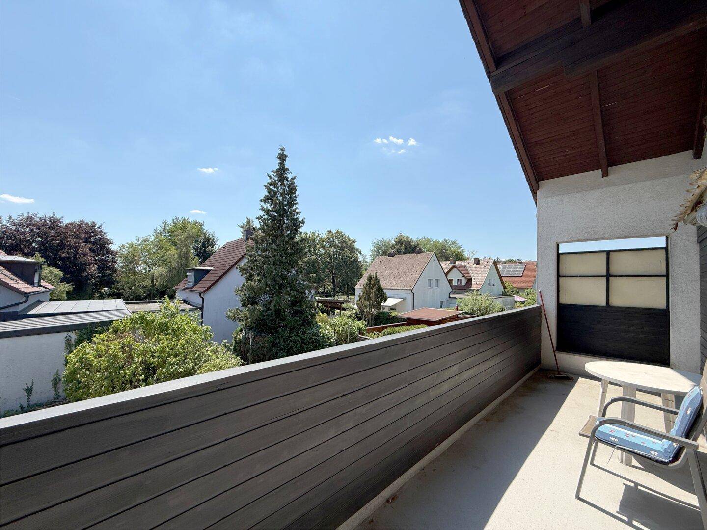 Sonniger Balkon mit Holzboden und weitem Blick über die Umgebung.