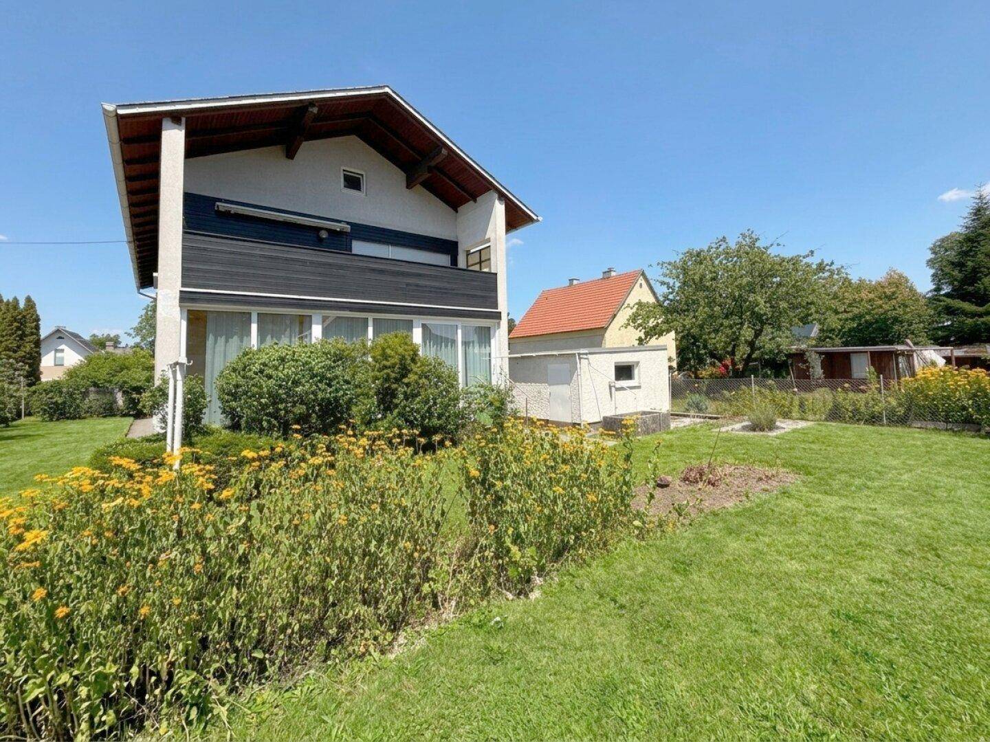 Großer Garten mit blühenden Pflanzen und Blick auf die Hausfassade.
